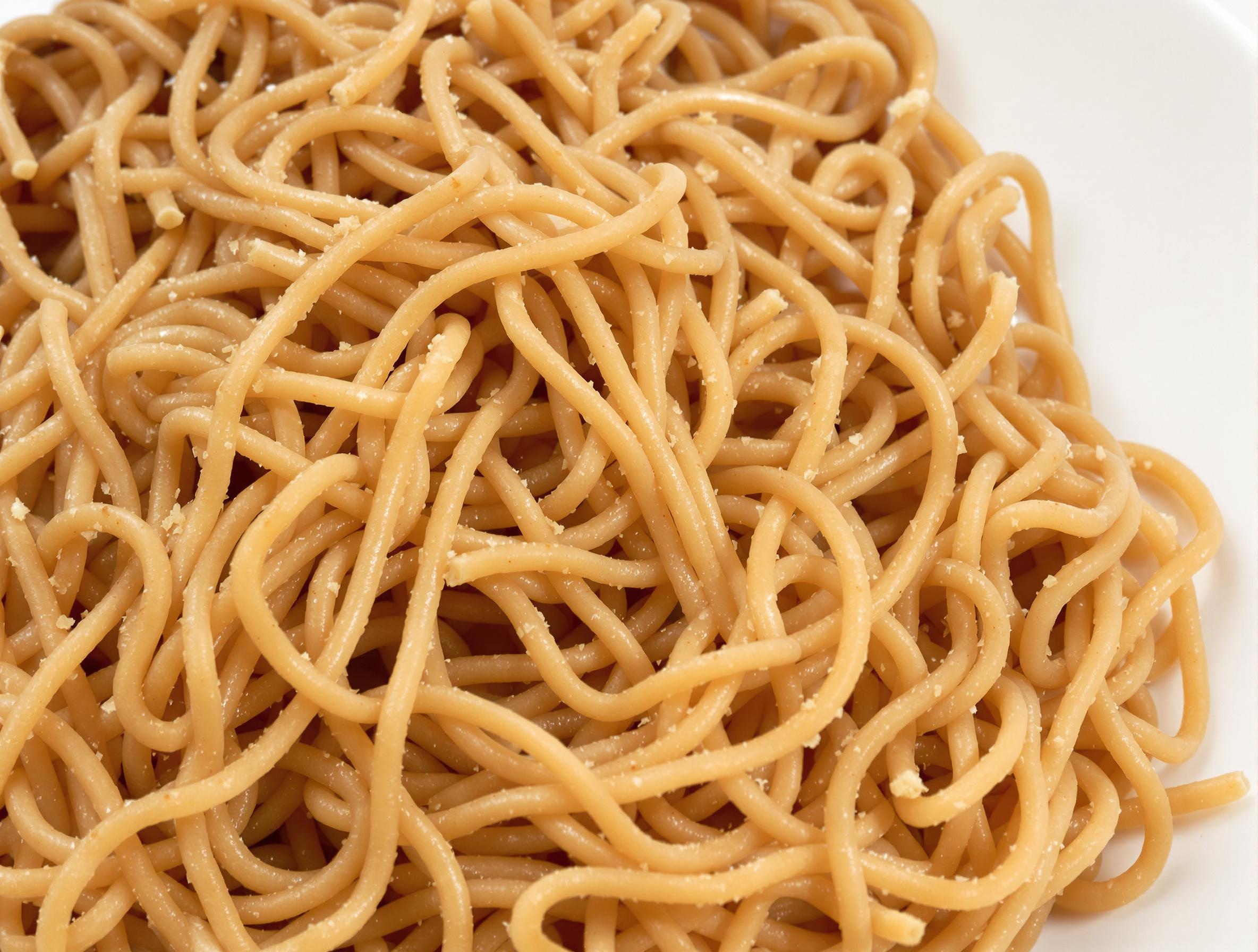 Portion standard de spaghetti complets cuits al dente, couleur sombre due au blé complet.