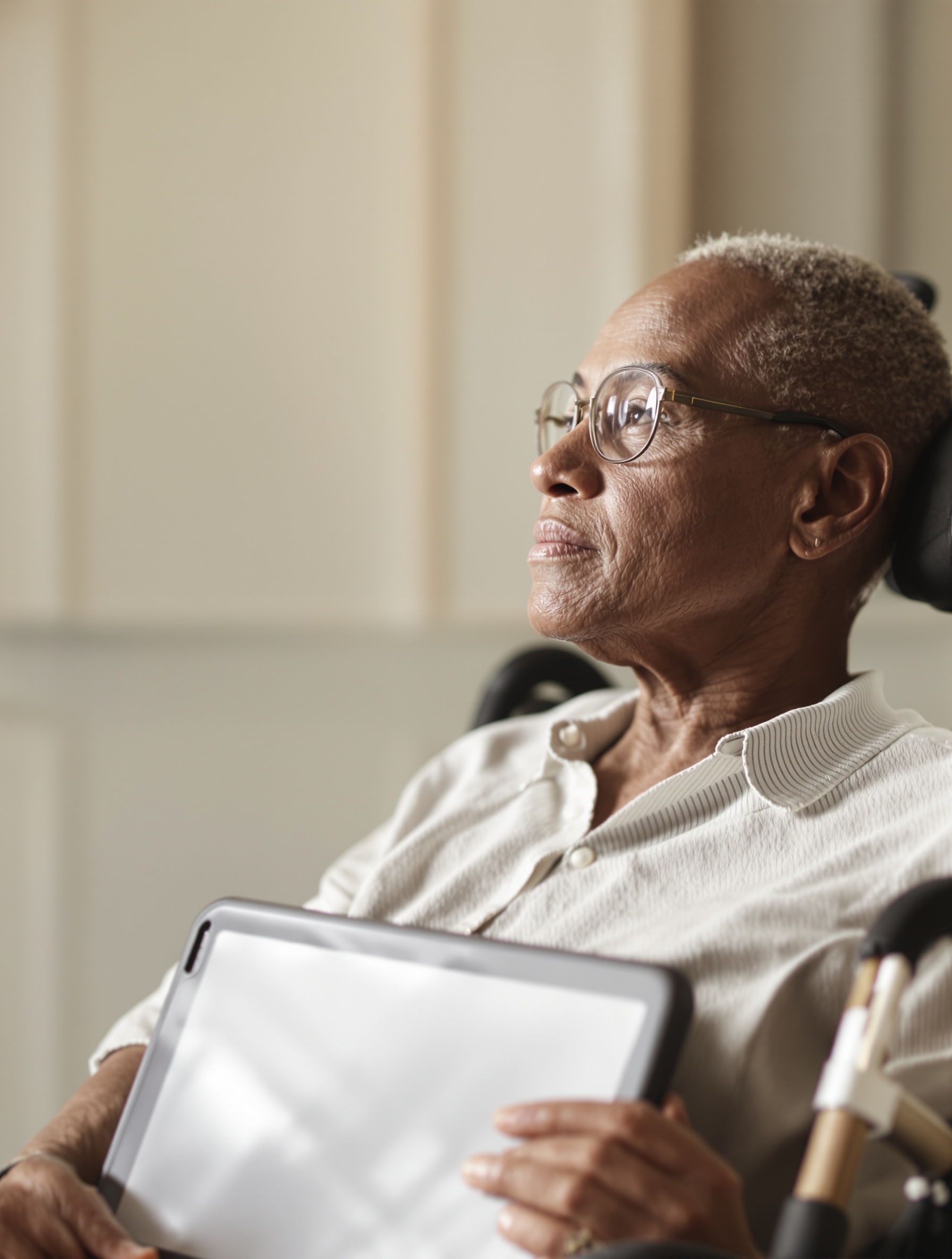 Visage serein d’une personne en fauteuil roulant regardant l’horizon avec tablette de communication, symbole de résilience SLA.