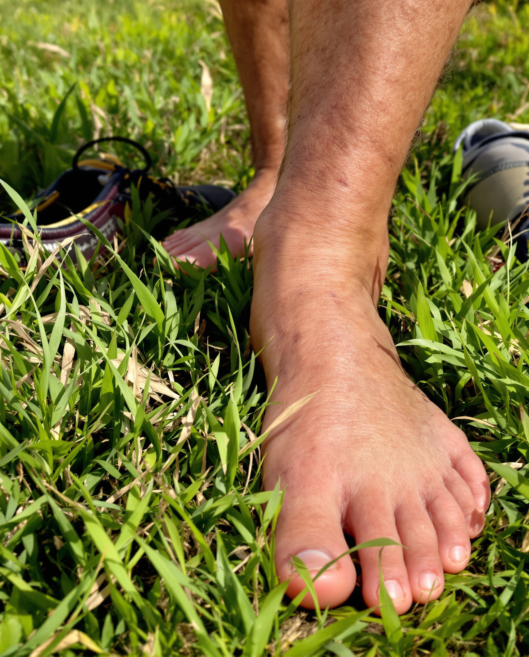 Premier pas : pieds d'une personne âgée sur l'herbe près de chaussures de marche